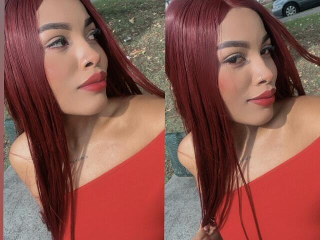 LexieBloom has red hair, light skin, and wears red lipstick with a subtle nose piercing. She's in a red top, showing off her tits in two side-by-side shots.