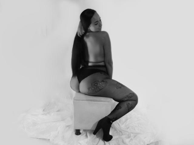 AmberRousell est assise sur un tabouret, dos à la caméra, vêtue de bas en dentelle noire à motifs floraux, de talons hauts, et ne porte rien sur le haut du corps, exposant ainsi ses fesses et ses longs cheveux noirs..