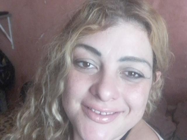 CrislimaJb has curly blonde hair, light skin, and a slight smile with glossy pink lips. She's wearing dark eyeliner and has small, dark eyebrows. Her nose is slightly upturned.
