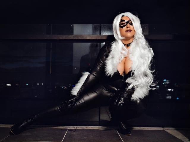 EvangelineAx in black leather outfit, white fur collar, and white wig, crouching with legs spread, black mask, showing large tits, black boots, and dark makeup, night city background.