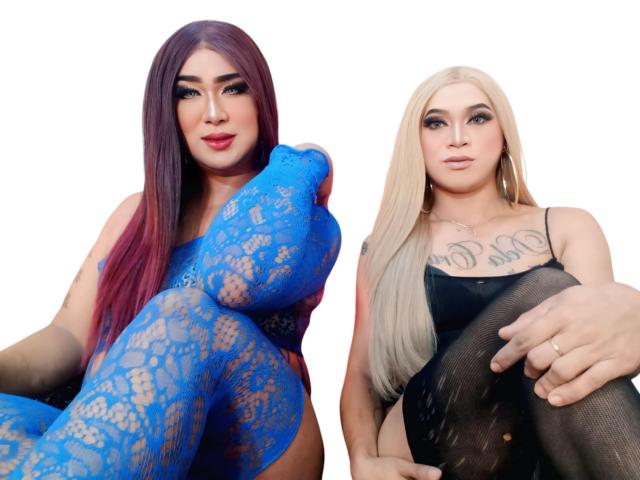Due ragazze filippine attraenti con i capelli lunghi, una con calze di pizzo blu che mostrano i seni, l'altra con una rete nera, entrambe con tatuaggi e espressioni sicure, sedute una accanto all'altra..