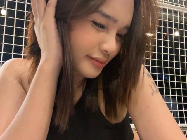 FreshYoungTS-hot with brown hair, black tank top, hand in hair, slight smile, tattoo on right arm, cute Asian woman, soft lighting, medium shot, relaxed, confident, sexy.