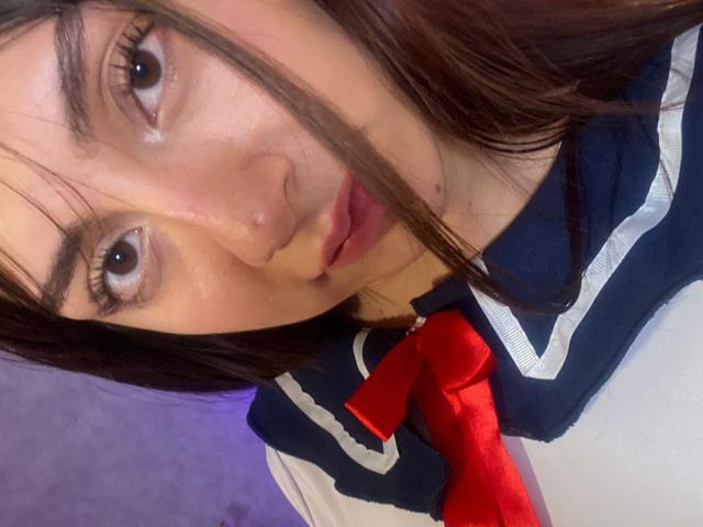 Luluberrie has a cute, slightly sweaty face with brown eyes, dark brown hair, and is wearing a Japanese schoolgirl uniform with a red ribbon. Her lips are slightly parted.
