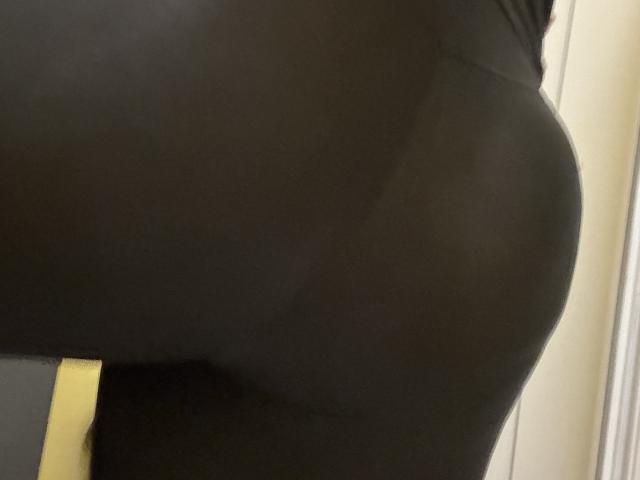 Barbarica's black, tight, shiny butt is in the foreground, showing smooth, reflective skin and a slight curve, captured in a low-angle, side-view shot.