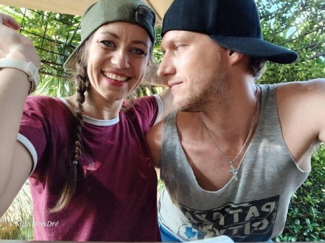 MissmeanDre with braids in a red shirt and MissmeanDre in a grey tank top and black cap, smiling and taking a selfie, both with visible tattoos.