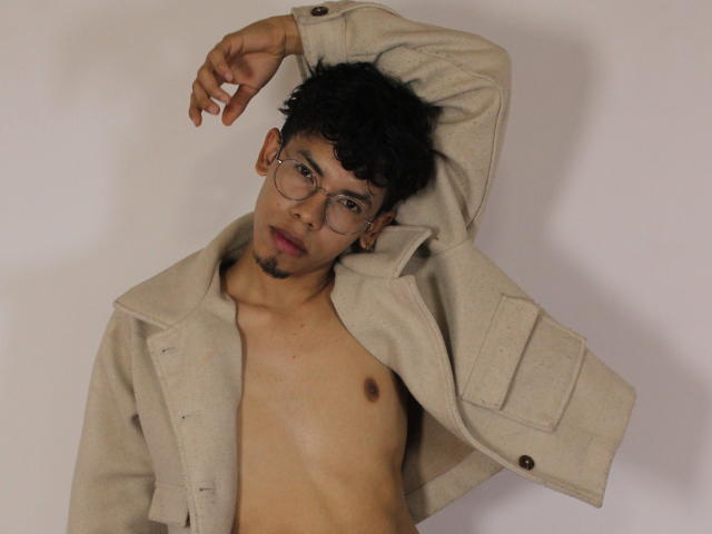LianStonne, shirtless, wearing beige coat, arm raised, glasses, dark curly hair, light brown skin, small nipples, slightly open mouth, looking at camera, slight beard, white background.
