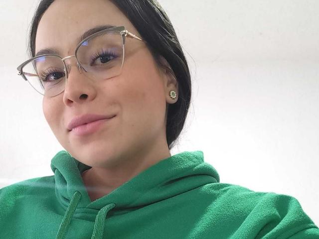 MartinaMarX heeft een lichte huid, zwart haar en draagt een bril, met een lichte glimlach. Ze draagt een groene hoodie, waardoor haar kleine neus en roze lippen zichtbaar zijn. Haar borsten zijn niet zichtbaar..