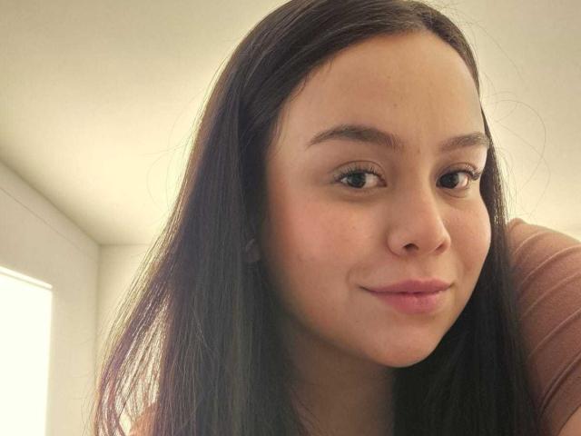 MartinaMarX heeft een lichtbruine huid, lang zwart haar en een lichte glimlach met roze lippen. Haar bruine ogen kijken naar de camera en laten een schattig en ontspannen gezicht zien..