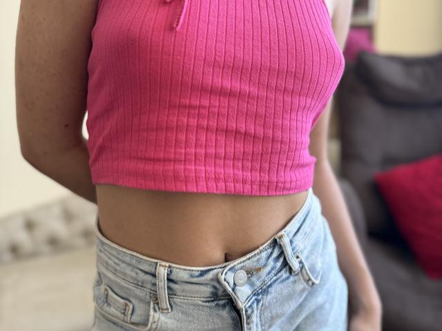 SofiVernara's pink ribbed crop top showing her small tits, paired with light blue denim shorts, exposing her flat, toned stomach and a hint of her waist.
