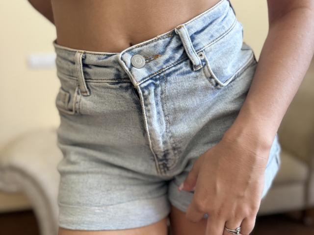 SofiVernara's light blue denim shorts are buttoned at the top, showing her bare midriff and hand with a ring, standing with her ass slightly tucked in.