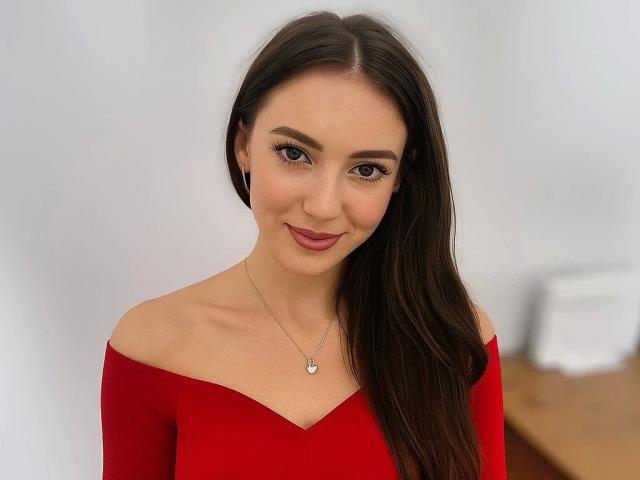 HarperSexy-hot with long brown hair, red off-shoulder top, and subtle smile, wearing a delicate necklace, has cute tits and a cute ass.