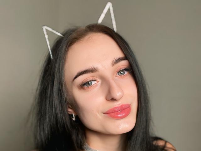 AnaLand has pale skin, black hair, blue eyes, and pink glossy lips, wearing white cat ears with a slight smile, showing a cute and sexy look.