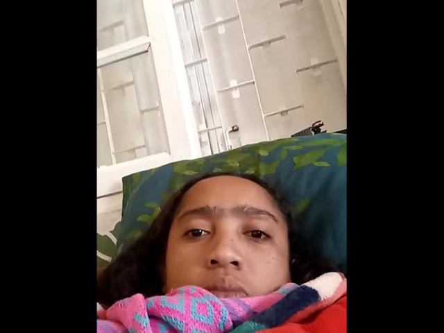 Stylized, minimalistic illustration of a coat of arms with a bold, white emblem on a dark, flat background. Red and pink accents at bottom. Clean, geometric lines.