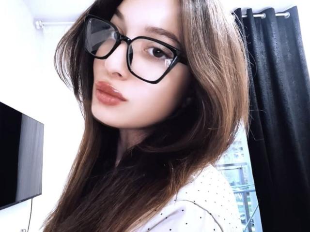 Kripkoa, avec ses longs cheveux bruns, ses lunettes noires et sa chemise blanche à pois, a des lèvres rouges et pulpeuses et un joli visage. Elle montre légèrement ses seins dans son autoportrait..