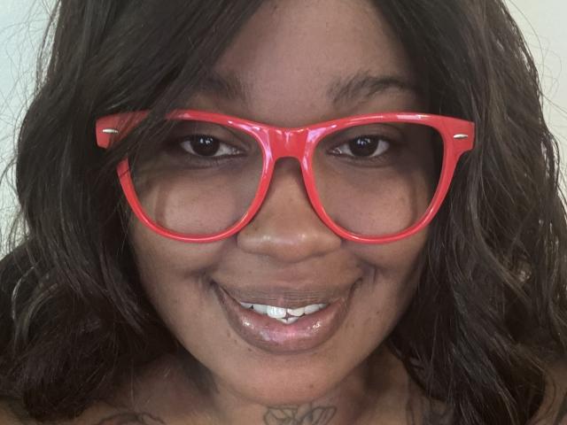 Shabrim, avec ses cheveux bruns foncés et ondulés, porte des lunettes rouges brillantes et sourit, montrant ses dents blanches. On peut apercevoir un petit tatouage sur son cou. Sa peau est foncée et elle a un visage mignon..