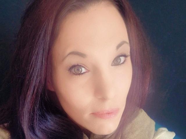 SexyAnnabell38-hot has light skin, green eyes, and dark purple hair, with subtle makeup and a soft smile. She's wearing a beige top, looking directly at the camera.