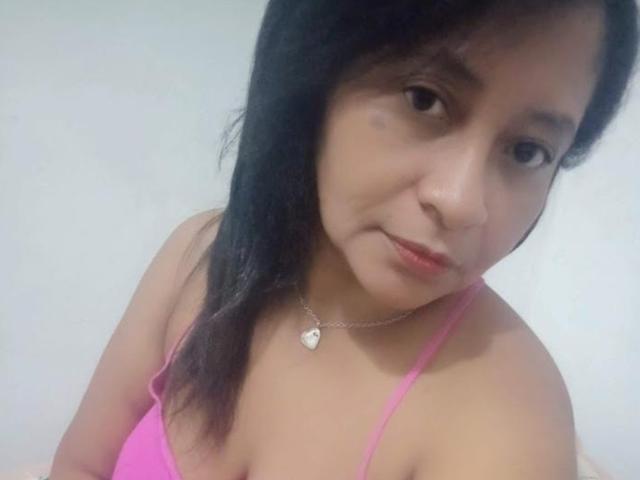 ShareLonnie with black hair, light skin, small breasts, wearing a pink bra, silver necklace with heart pendant, slight smile, and a small bruise on her right cheek.