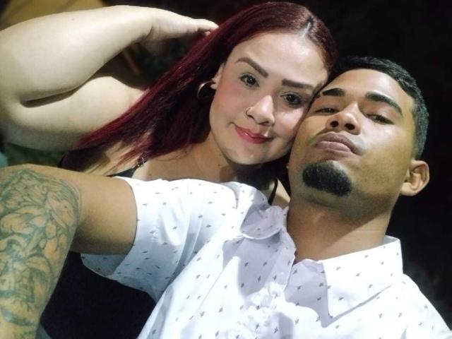 FrankAndkattyLu with red hair and FrankAndkattyLu with dark hair, both smiling. Red-haired FrankAndkattyLu's arm around tattooed FrankAndkattyLu, wearing white shirt with small patterns. FrankAndkattyLu has goatee.