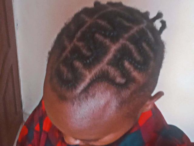 InfinityCouple's dark brown skin, short twisted Afro hairstyle with a unique pattern, and shiny forehead, wearing a red and blue checkered shirt, has a slightly tilted head.