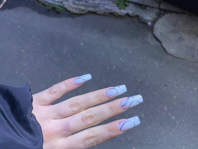 La mano di Kripkoa, con unghie lunghe, bianche e appuntite, presenta linee curve blu. Le sue dita sono leggermente divaricate su una superficie grigia e strutturata. Indossa una manica nera..