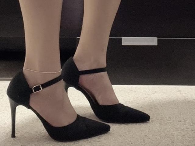 GoddessFreya69's legs in black, pointed-toe, high-heeled shoes with a thin strap and small buckle. She's wearing sheer, pale stockings and a delicate ankle bracelet.