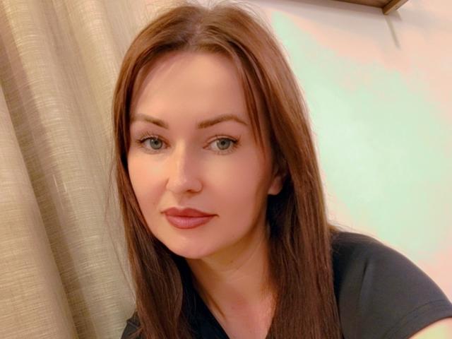 TessieNeta has straight brown hair, blue eyes, and a slight smile with pink lips. She's wearing a black shirt, looking cute and fresh.