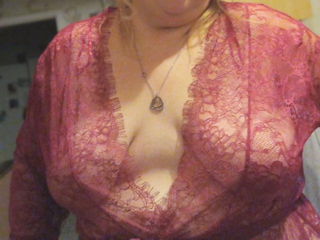 KleinerTeufel82-hot in a pink lace robe, revealing large, bare boobs with a deep V-neck, wearing a silver necklace with a teardrop pendant.