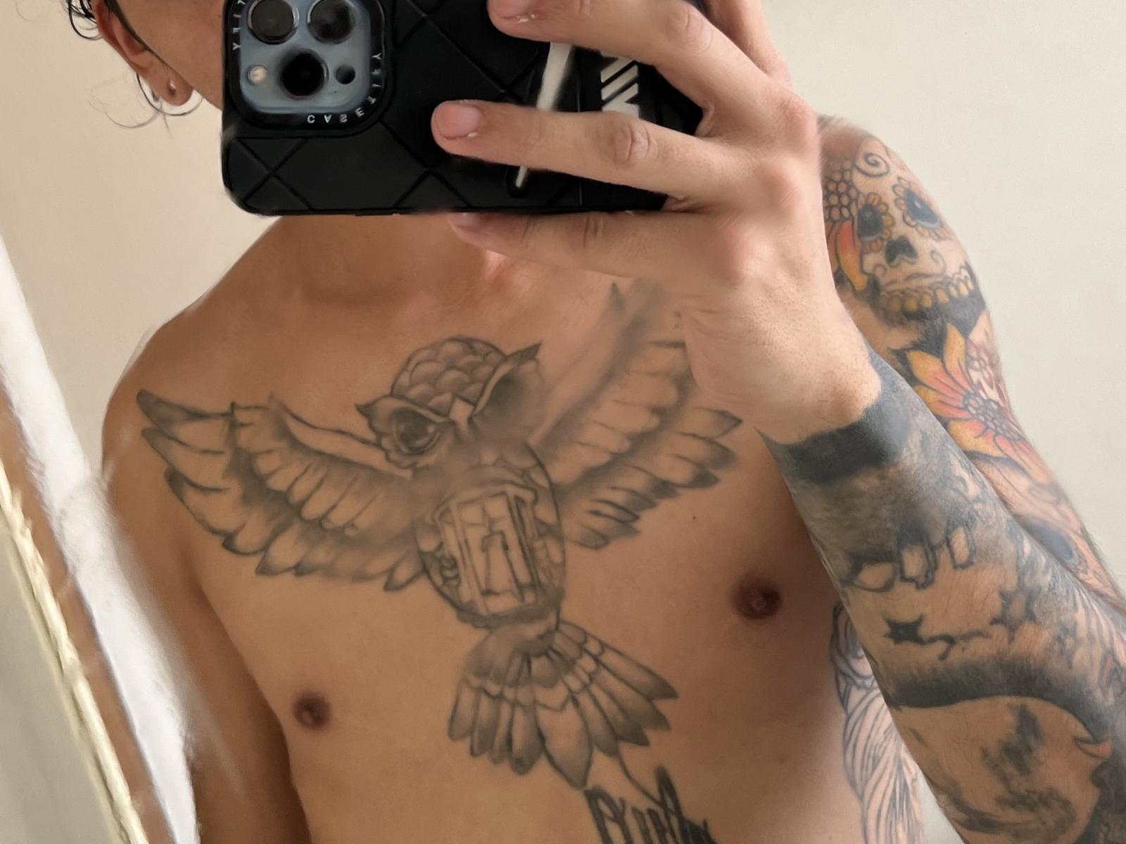 BrethMan69's chest tattoo of a detailed eagle with wings spread, above a shield, and right arm tattoo of a skull with colorful, intricate designs. BrethMan69's holding a phone.