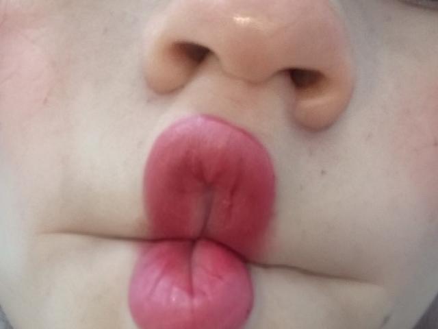 SaritaWilde's pink pout with slightly parted lips, showing a small bit of her upper lip, and a pale, pinkish nose above her glossy, pinkish-red lips.