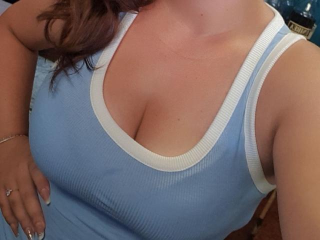 HottieBLove's large, round tits in a tight, light blue rib tank top with white trim, showing noticeable cleavage, and wearing a silver bracelet and ring.