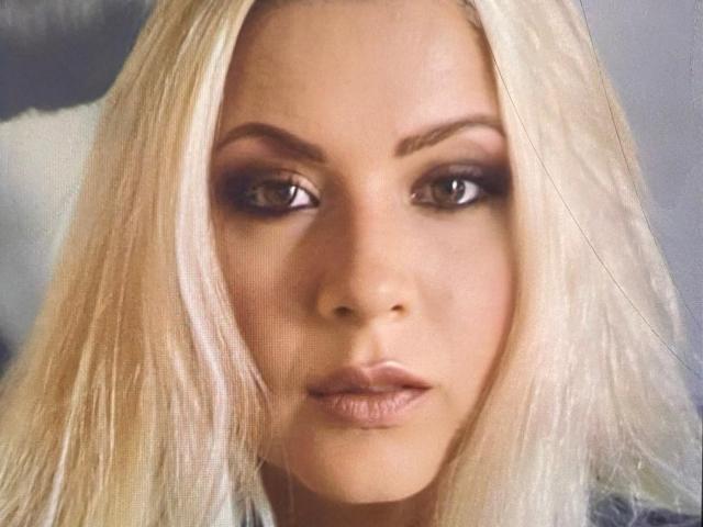 KarlaGodessTS has blonde hair, brown eyes, and full lips with a serious expression. Her makeup includes dark eyeliner and nude lipstick. Her ass is not visible.