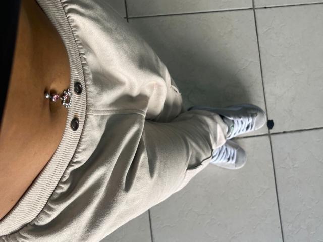 MyaaTyler's tan belly with a navel piercing, wearing light gray sweatpants and white sneakers, standing on tiled floor. Boobs not visible, focus on lower body.