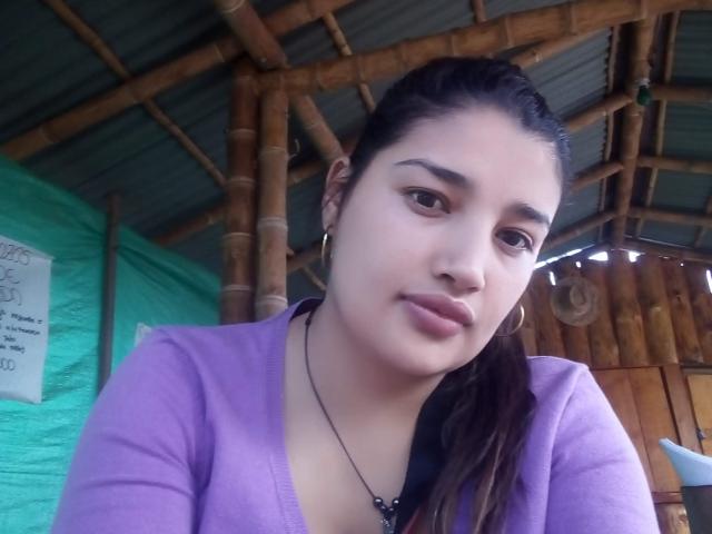 ZafiRouge has a cute face with medium brown skin, dark brown eyes, and black hair in a ponytail. She's wearing a purple top, hoop earrings, and a black necklace.