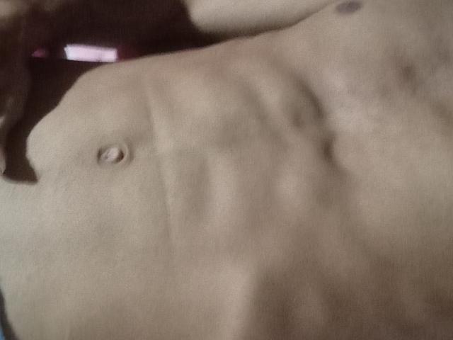 Morenhoh's bare, toned torso with visible ribs and small, erect nipple on the left side, in a soft, dimly lit photograph. Morenhoh's skin is light brown.
