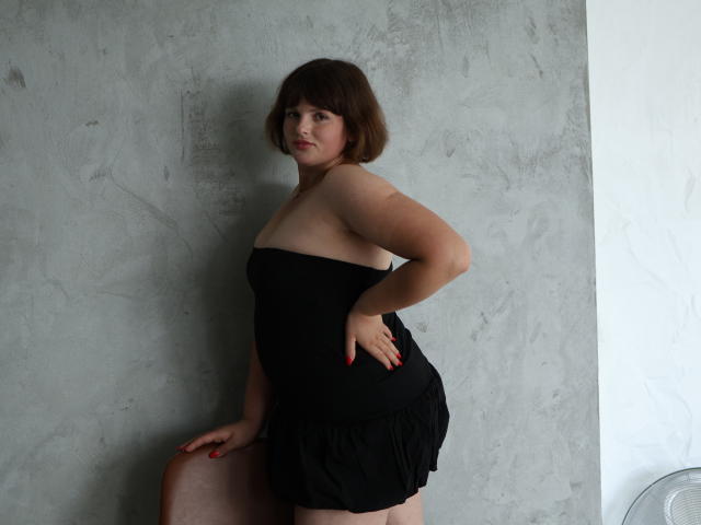 StaceyLex is holding a large, detailed, red and black, minimalist coat of arms. The coat arms are centered with a bold, symmetrical design. The background is plain.