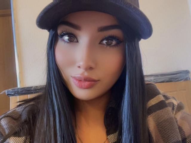 Lilly Taylor tiene el cabello oscuro y lacio, ojos marrones y labios rosados y carnosos. Lleva un gorro gris y una camisa de cuadros. Su maquillaje es llamativo, con pestañas largas..