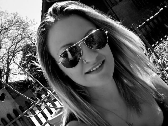 Swissmiss88-hot has long, straight hair, wearing reflective sunglasses, and a nose ring, smiling with visible teeth, showing a cute, attractive face, in a black-and-white photo.
