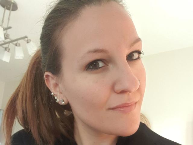 Swissmiss88-hot has a cute face with a nose piercing, brown eyes, long brown ponytail, and is wearing small diamond earrings. She's smiling with a slight pinkish nose.