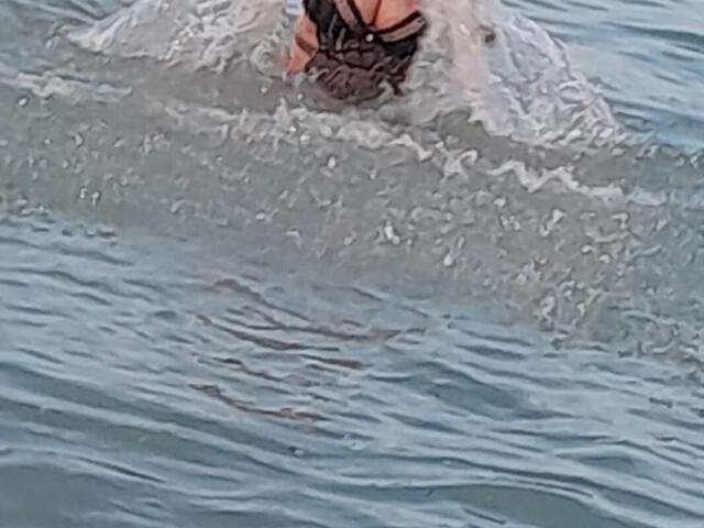 BlissSophia's ass is submerged in water, with her black strappy swimsuit visible above the surface, creating splashes around her.