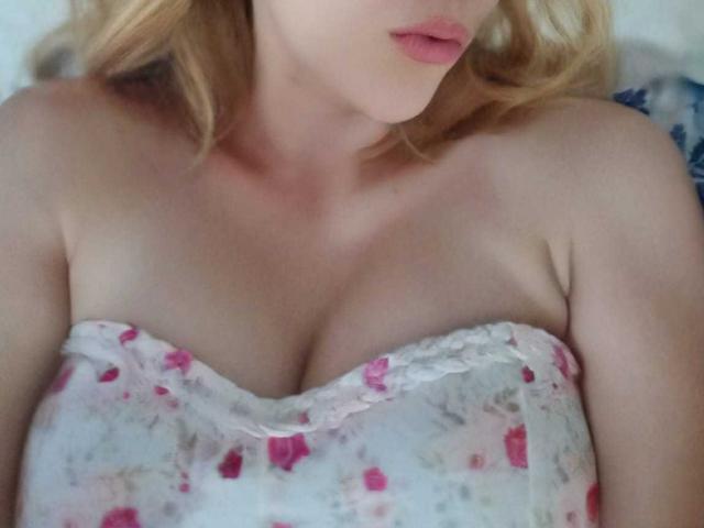 LaSexyest has light skin, blonde hair, and is wearing a strapless floral dress that reveals her tits. Her pink lips are slightly parted.