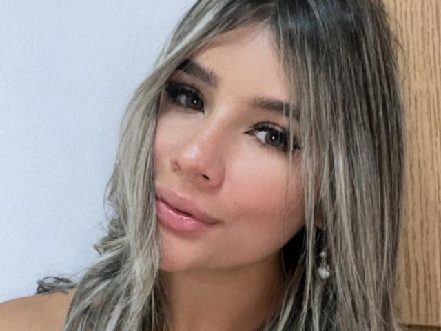 SashaPolet has a cute face with shiny, straight, gray-blonde hair, full pink lips, and dark, thick eyebrows. Her eyes are slightly upturned, with long, black lashes.