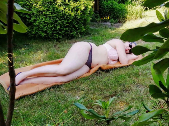 Nilswinger24-hot, lying on a brown blanket, wearing pink bra and black panties, with large ass and pale skin, on grass, surrounded by green leaves, sunbathing.