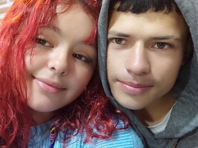 LoveAndMadness with curly red hair and pink lips, smiling next to LoveAndMadness with brown hair and gray hoodie, both with light skin and subtle makeup.