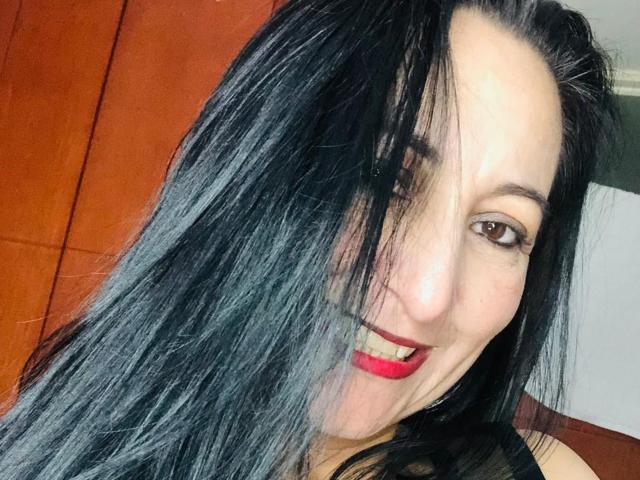 SofiaKingg has long black hair, red lipstick, and a slight smile with her hair partially covering her right eye. Her brown eyes are visible. She has pale skin.