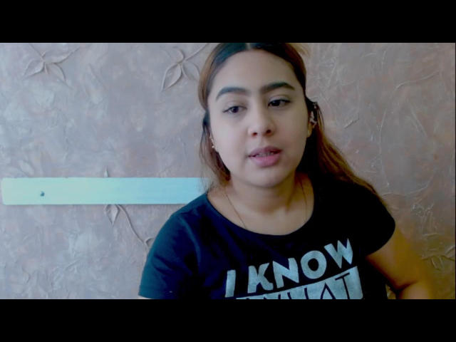 MiaBonnett, a chubby woman with long brown hair, wearing a black shirt with "I KNOW MYST" text, has small tits and a slightly open mouth in a selfie.