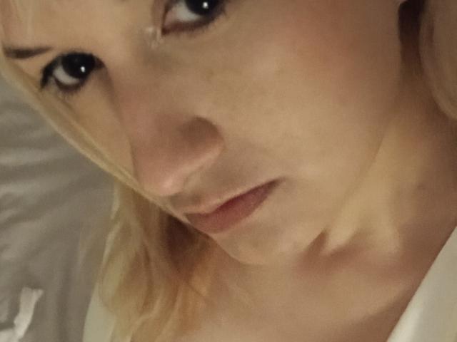 A selfie of LuzyHot with her pouty, slightly worried face and blonde hair, showing her nose, lips, and upper chest, with visible freckles and subtle makeup.