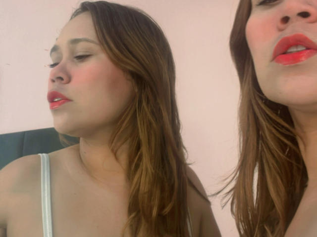 SophiaQueens has red lipstick, closed eyes, and brown hair, wearing a white tank top, showing her tits in two side-by-side selfies.