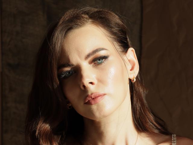 TinaPeachX heeft een glanzende huid, blauwe ogen en bruin haar, draagt kleine gouden oorbellen, en heeft een serieuze, licht vochtige uitstraling, met zachte, volmaakte lippen..