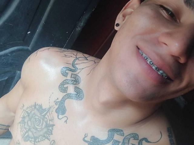 Peter Jonies, con un petto lucido e sudatore, denti di metallo argentato e molteplici tatuaggi di serpenti, sorride alla macchina fotografica. Al suo orecchio c'è un piercing a forma di buco nero..