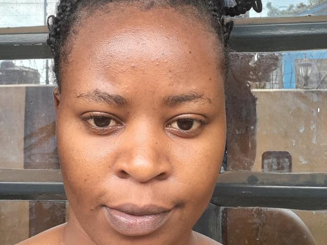 QueenBoobby has a dark brown complexion, small nose, slightly parted lips, and curly black hair. Her brown eyes are looking forward with a subtle, calm expression.